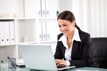 Smiling successful businesswoman working on laptop