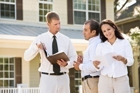 Real estate agent showing brochure of house to Hispanic couple