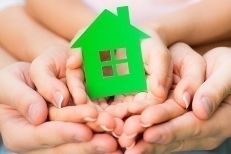 Family holding green paper house