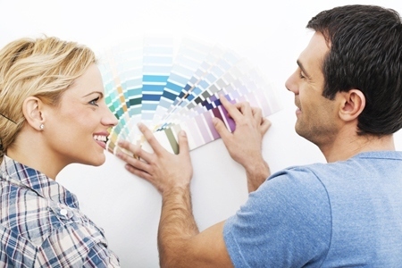 Mid adult couple holding paint swatches.