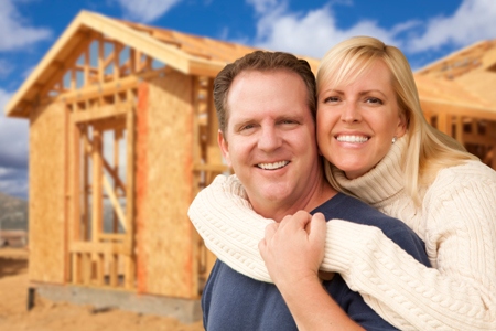 Happy Excited Couple in Front of Their New Home Construction Framing Site.