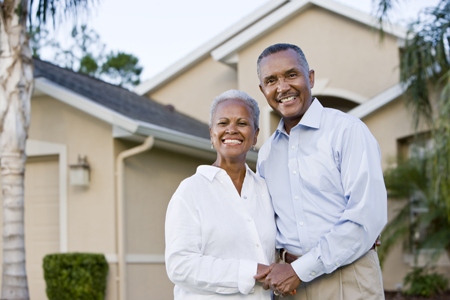 Portrait of happy African American couple standing outside home