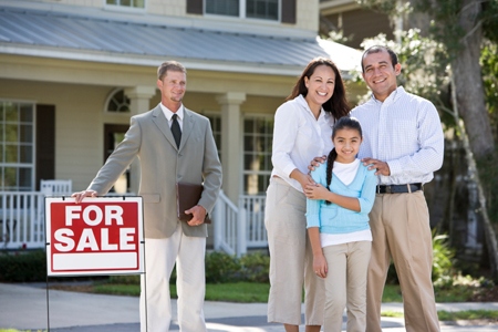 Hispanic family outside house for sale with real estate agent