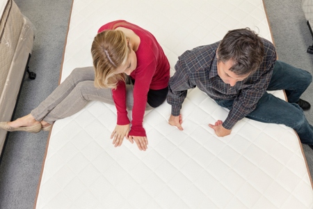 Friends sitting on mattress in furniture store