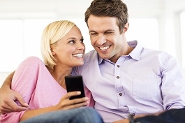 Couple Using Smart Phone Together At House